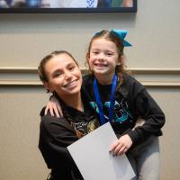 Izzy hugs Sky Katz and they smile for a photo.