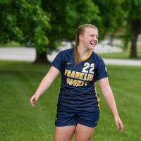 Amelia Wells, a fifteen year old girl with strawberry blonde hair, smiles while posing in her Franklin County High School soccer uniform.