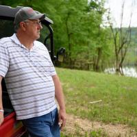 Danny leans against his golf cart as he stares out into the lake.