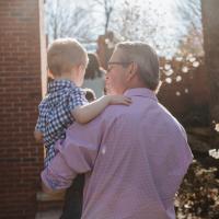 Using one arm, Dr. Johnson carries his grandson outside.