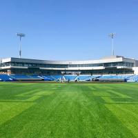 A baseball stadium with blue seats and a bright green field.