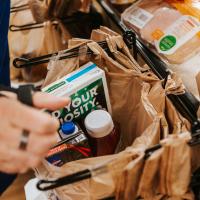 A close-up of Donald’s hands as he bags groceries at a Kroger check-out.