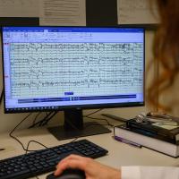 Dr. Bensalem-Owen uses a mouse on a computer to display a screen of brainwaves.