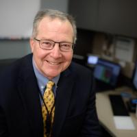 Dr. Mullett sits at a work station and smiles.