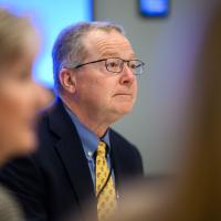 Dr. Mullett listens attentively to a colleague speaking.