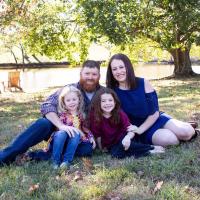 Izzy's family sits on the ground together for a family photo.