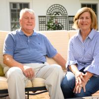 E and Cary sit on a yellow couch on their porch.