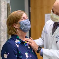 Dr. Ueland palpates E’s throat during an exam.