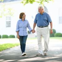 E and Cary walk down their drive, holding hands and smiling at each other.