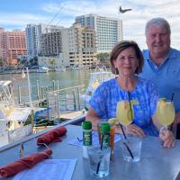 A photo of E and Cary on vacation, posing behind a table adjacent to an ocean.