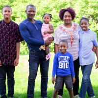 A photo of the entire Kargbo family posing together outside.