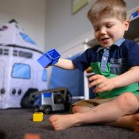 A candid photo of Everett sitting on the floor and playing with his toy truck.