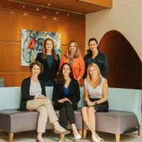 A group photo of the Pediatric Advanced Care team smiling as they pose together in their office.