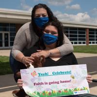 Faith's mom hugs her while Faith holds a sign from her nurses that says \