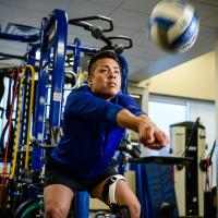 Gil practices bumping the volleyball while wearing his knee brace.