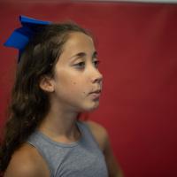 A close-up portrait of Gracie looking fierce and determined while wearing a bright blue bow. She is shown in profile.