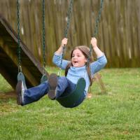 Henley smiles as she swings back and forth on a playground.