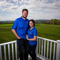 Jacob and his wife Allison lean against their porch railing and smile for a photo.