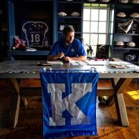 Jacob sits behind his desk which is decorated with paraphernalia from his football playing days.