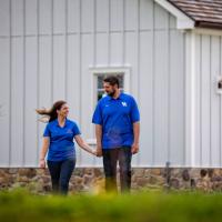 Jacob holds hands with his wife and walks across their yard.