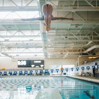 A photo of Jaida mid-dive, her head and feet meeting in the air as she flips into the pool.