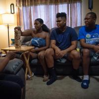 Jerome, his wife Jeanine, and their two teenage children sit in their living room, playing a game of Jenga.