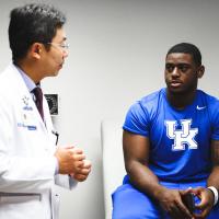 Josh and Dr. Peng Wang discuss his cancer in an examination room.