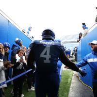 Josh high five's a coach while walking out to the football field in his uniform and gear.