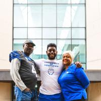 Josh hugs his mom and dad and smiles outside of the hospital.