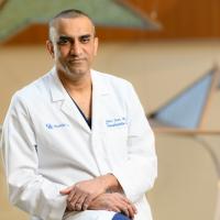 Dr. Malay Shah, a middle-aged South Asian man with short black hair, stands wearing his white doctor’s coat in the Kentucky Children’s Hospital lobby.