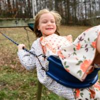 Julie wears a big smile as she swings up the air on a playground.