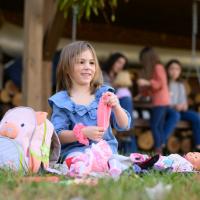 A candid photo of Kailey playing with some of her toys while sitting in the grass.