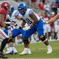 An action shot of Kenneth playing football. He is wearing the full football uniform and protective gear.