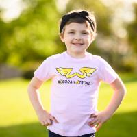 A close-up of Leorah at a park, smiling and standing confidently with her hands on her hips.