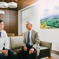 Dr. Charles Lutz seated on a bench having a conversation with Dr. Peng Wang.