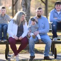 The Baker family poses for a photo, sitting at a picnic table at a park. Felicia, MaKenzie and Tyler in the front, accompanied by MaKenzie’s brothers: ten-year-old Westin, wearing a grey sweater with jeans, and 11-year-old Gage, in a blue sweater with jeans.