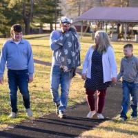 MaKenzie closes her eyes and lays her head on her dad's shoulder as the Baker family walks together.