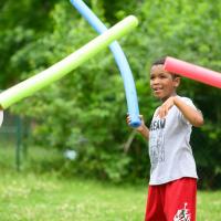 A candid photo of Malakai having a pool noodle fight outside with some of his friends.