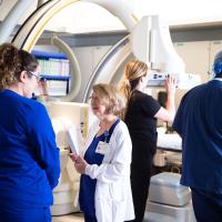 Margie talks with a nurse in a room with an x-ray machine behind them.