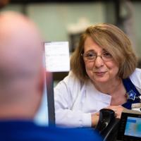 Margie leans over a desk to talk to the nurse behind the desk.