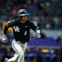 Marshall running across the baseball field in a black and gray UK baseball uniform, including a black helmet and grey gloves.