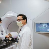 Marshall works on a radiation machine in the background as Dr. Pohkrel turns to the side, showing us his profile.