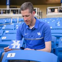 A candid photo of Matt reading a note while sitting in the stands of the stadium.