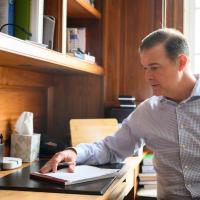 A candid photo of Coach Mitchell at his desk, looking at some papers.