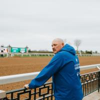 A photo of Matt looking down the race track as he leans against the railing.