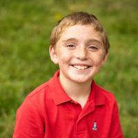 A portrait of Max, smiling broadly and wearing a red polo shirt.