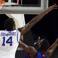 An action shot of Michael jumping in the air to block a Kansas basketball player from dunking the ball.