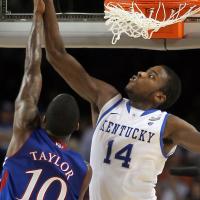 An action shot of Michael in mid-air blocking a Kansas basketball player from scoring.