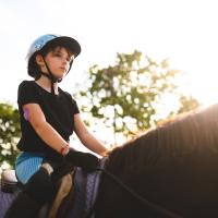 Kara rides her horse. Her insulin pump is visible on the back of her upper arm.