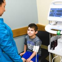 Max sits in a chair and has his blood pressure taken by a nurse.